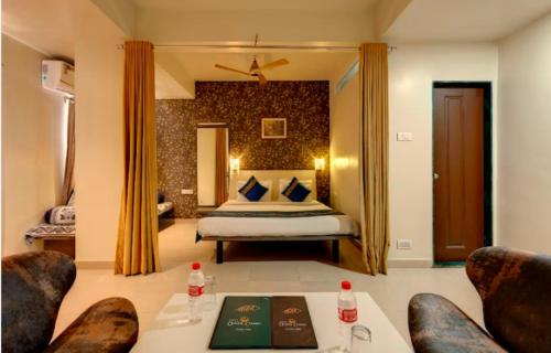 a hotel room with a bed and two chairs at Hotel Orient Crown, Kolhapur in Kolhapur