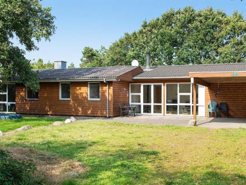 a wooden house with a large patio in front of it at 8 person holiday home in Blåvand in Blåvand