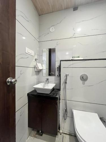 a white bathroom with a sink and a mirror at Jeel Pearl Hotel in Udaipur