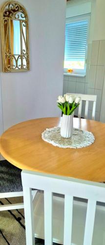 a table with a vase of white flowers on it at Apartman Stanković in Teslić