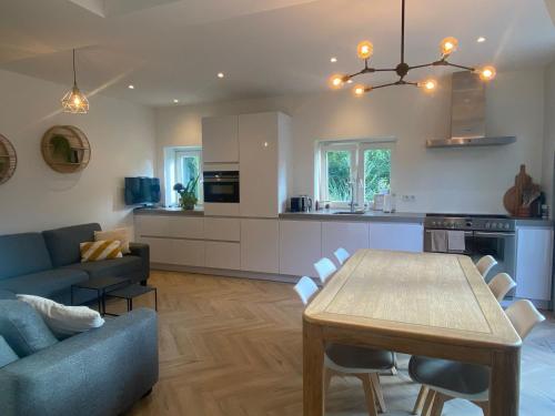 a kitchen and living room with a table and a couch at Ons Huisje Achter in Noordwijkerhout