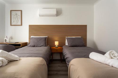 a room with two beds and a table with a lamp at Linda s Guest House Alojamento 2 in Costa da Caparica