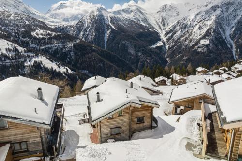 a snow covered village with mountains in the background at Chalet mit Sauna an der Piste in Rosswald