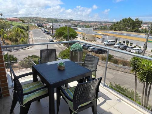 a table and chairs on a balcony with a view of a street at Stylish & Spacious Apartment with Balcony in Lourinhã