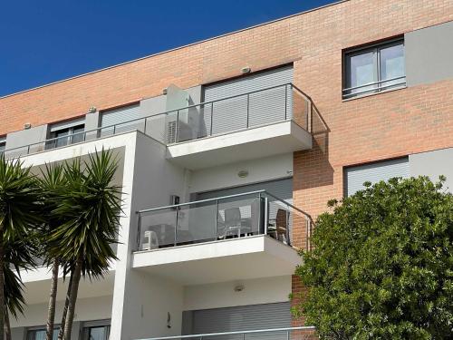 an apartment building with a balcony with chairs on it at Stylish & Spacious Apartment with Balcony in Lourinhã