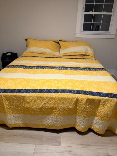 a bed with a yellow blanket on top of it at Bala At the Beach - Somers Point, NJ in Somers Point