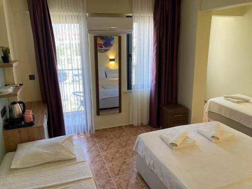 a hotel room with two beds and a mirror at Olimpia Hotel in Fethiye