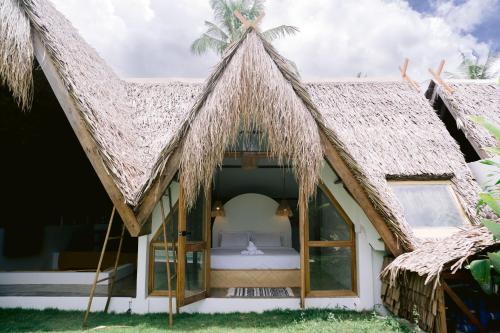 a bedroom in a thatch roofed house with a bed at Vibes Villas Siargao in General Luna