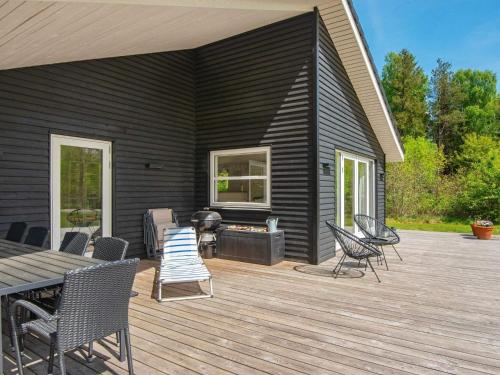 a black house with a deck with chairs and a table at 5 star holiday home in Silkeborg in Silkeborg