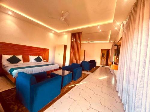 a hotel room with a bed and blue chairs at The Edge Retreat A Premium Property in Mussoorie