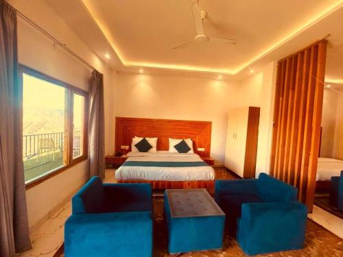 a hotel room with a bed and two blue chairs at The Edge Retreat A Premium Property in Mussoorie
