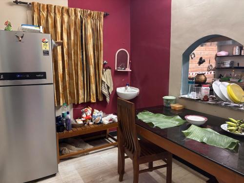 a kitchen with a counter with a refrigerator and a table at Aswin's Homestay 1bhk in Podanūr