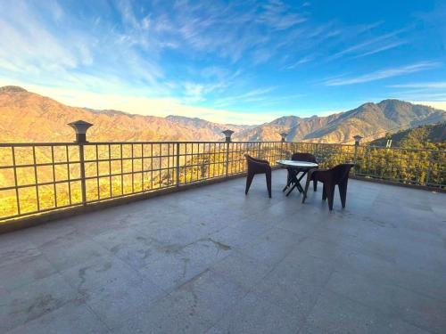 a table and chairs on a balcony with a view of mountains at The Edge Retreat A Premium Property in Mussoorie