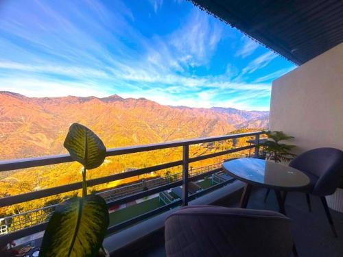 a balcony with a table and a view of mountains at The Edge Retreat A Premium Property in Mussoorie