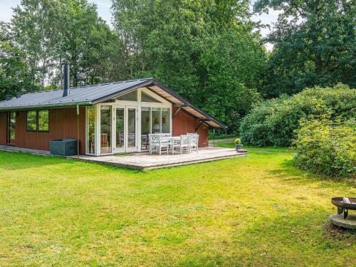 a small cabin with a deck in a yard at Tranquil Lakeside Retreat in Ry-By Traum in Ry