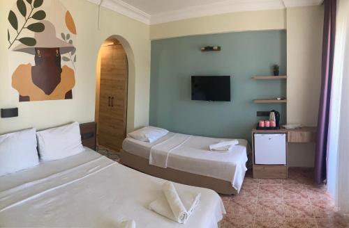 a hotel room with two beds and a tv at Olimpia Hotel in Fethiye