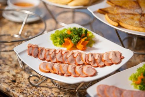 a plate of sausages and vegetables on a table at Hanoi Paon Hotel Spa & Sky Bar in Hanoi