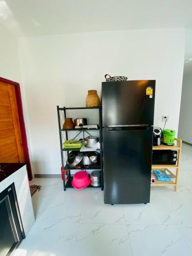 a kitchen with a black refrigerator in a room at Cher Cher Pool Villa in Ban Chang