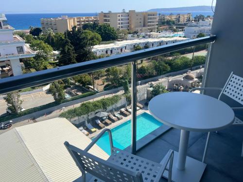 a balcony with a table and chairs and a pool at OSIRIS HOTEL APARTMENTS and STUDIOS in Ialyssos