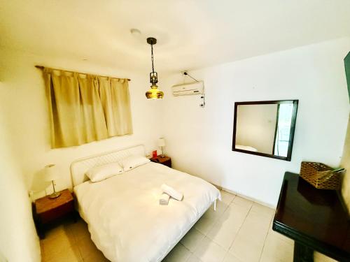 una camera da letto con un letto bianco e uno specchio di OASIS GARDEN a Eilat