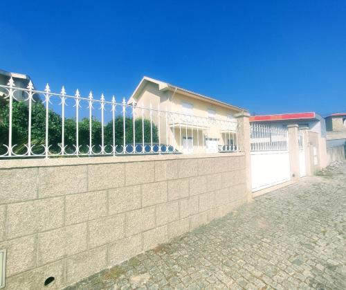 a fence on the side of a brick wall at Casa com jardim privado e estacionamento no interior in Amares