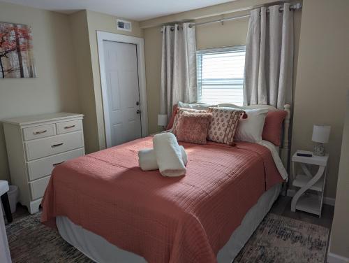 a bedroom with a bed with a red blanket and a window at The Calico Cottage in Lewis Center