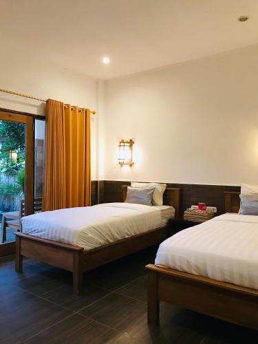 a bedroom with two beds and a window at Dili Gili in Gili Trawangan