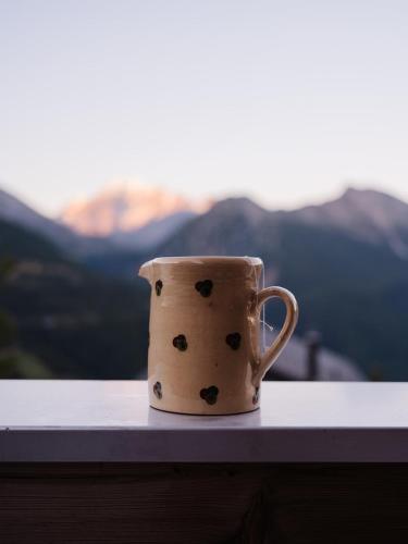 a coffee cup sitting on a window sill with mountains in the background at Chalet mit Sauna an der Piste in Rosswald