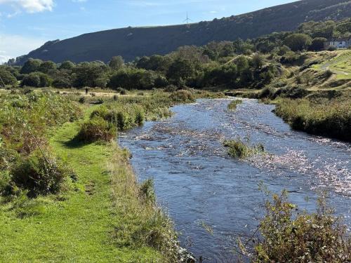 a river in a field with a hill in the background at Bedwellty Lodge near BikePark Wales in Tredegar
