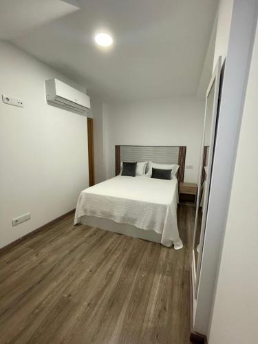 a bedroom with a white bed and wooden floors at Apartamento Paseo Malecón Planta 2 in Monforte de Lemos