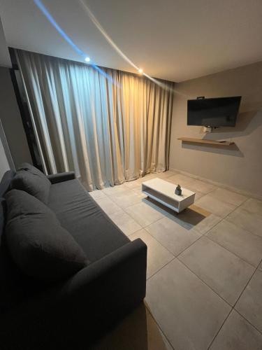 a living room with a couch and a flat screen tv at Depto vista directa al mar con Piscina climatizada in Necochea