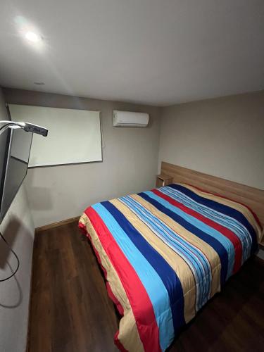 a bedroom with a bed with a colorful striped blanket at Depto vista directa al mar con Piscina climatizada in Necochea