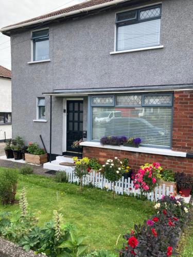a house with a white picket fence and flowers at North Coast Retreat in Portstewart