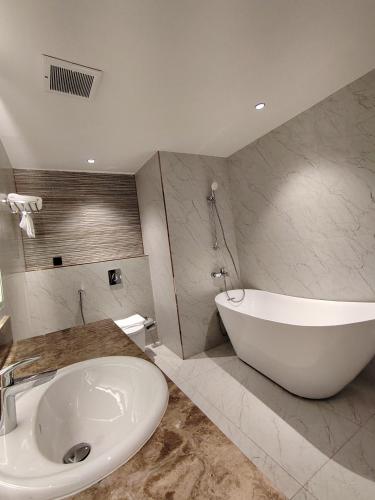 a bathroom with a large white tub and a sink at Samtinn Hotel King Fahad in Riyadh