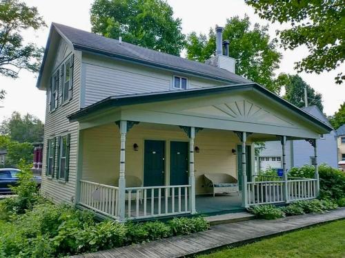 a small yellow house with a porch and a porch at Historic Devoe House-Walk to Downtown Arts and Restaurants in Wausau