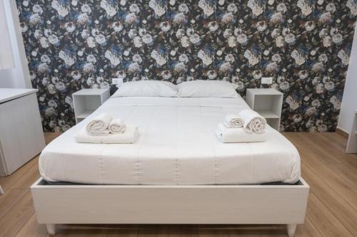 a white bed in a bedroom with a floral wallpaper at Bed and Breakfast Al Portanova in Reggio Calabria