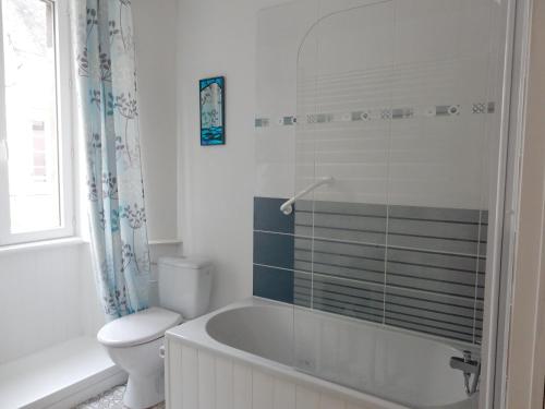 a white bathroom with a tub and a toilet at The LightHouse Chambres à louer in Châteaulin