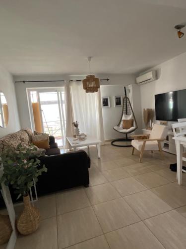 a living room with a black couch and a tv at Benidorm Breeze in Benidorm