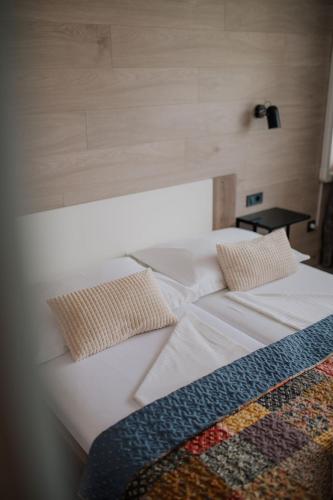a white bed with two pillows on top of it at Hotel Matija Gubec in Stubicke Toplice