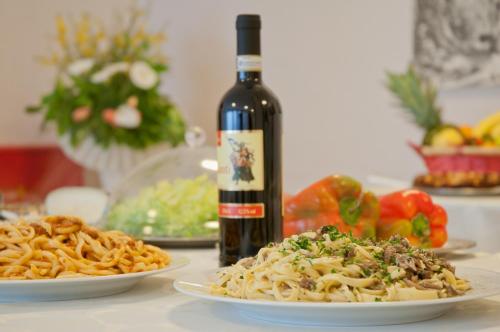 a bottle of wine sitting next to two plates of pasta at Albergo La Rosetta in Chianciano Terme