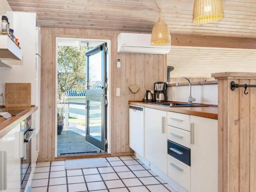 a kitchen with white cabinets and a sliding glass door at 4 star holiday home in Juelsminde in Sønderby