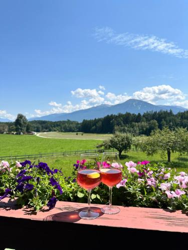 two glasses of wine sitting on a table with flowers at Landhotel Gasthof Eichhof Natters in Innsbruck