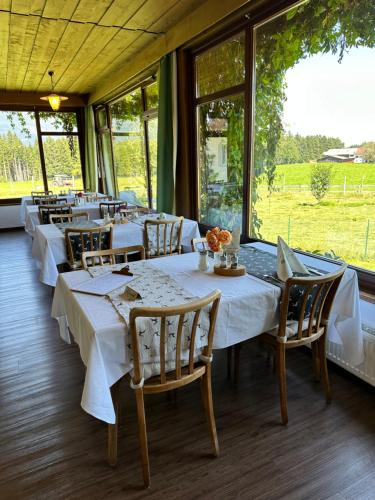 a dining room with white tables and chairs and windows at Landhotel Gasthof Eichhof Natters in Innsbruck