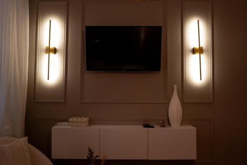 a living room with two lights and a tv on the wall at L'Exceptionnel in Reims