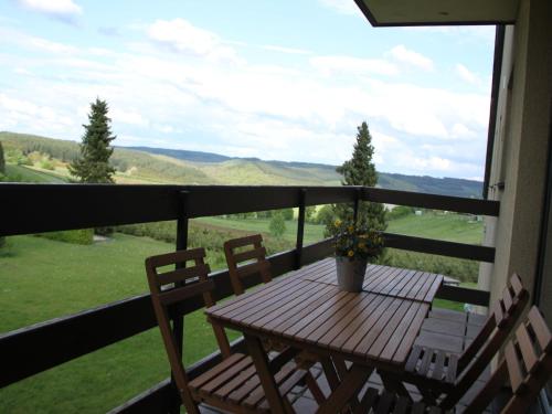 a wooden table and chairs on a balcony with a view at Family Apartment Bouillon and Semois River in Gros-Fays