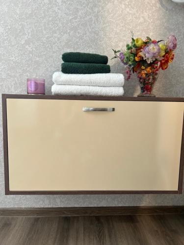 a shelf with towels and a vase of flowers at Guesthouse TEA in Kutaisi