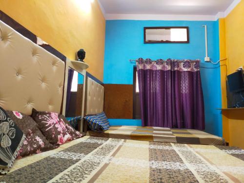 a bedroom with blue walls and purple curtains at Maa Vaishno Guest House in Varanasi