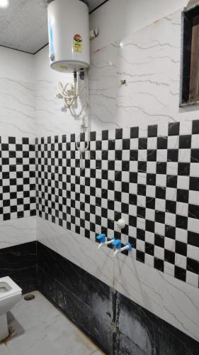 a bathroom with a black and white checkered wall at Shree Bankey Bihari Atithi Bhawan in Mathura