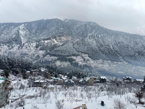 a snow covered mountain with a town in the foreground at Hotel Old Manali ,Monthly Room with Kitchen Only Rs 18000 in Manāli