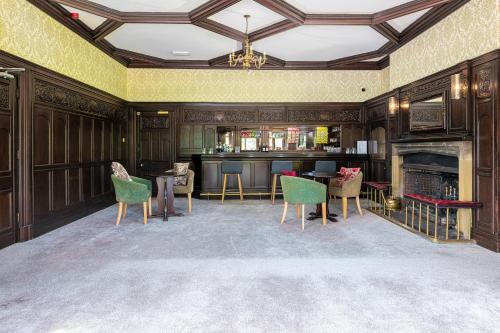 a room with a bar with chairs and a fireplace at Northop Hall Country House Hotel in Mold